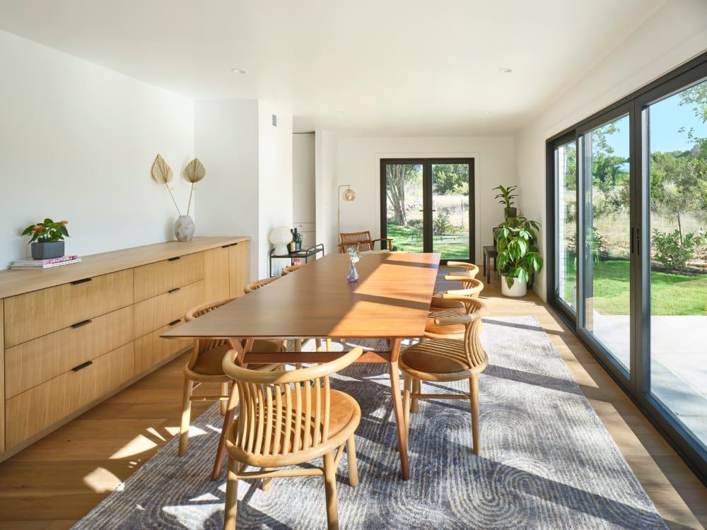 Dining room with a long white oak credenza with rows of drawers along one wall, and a wood dining table