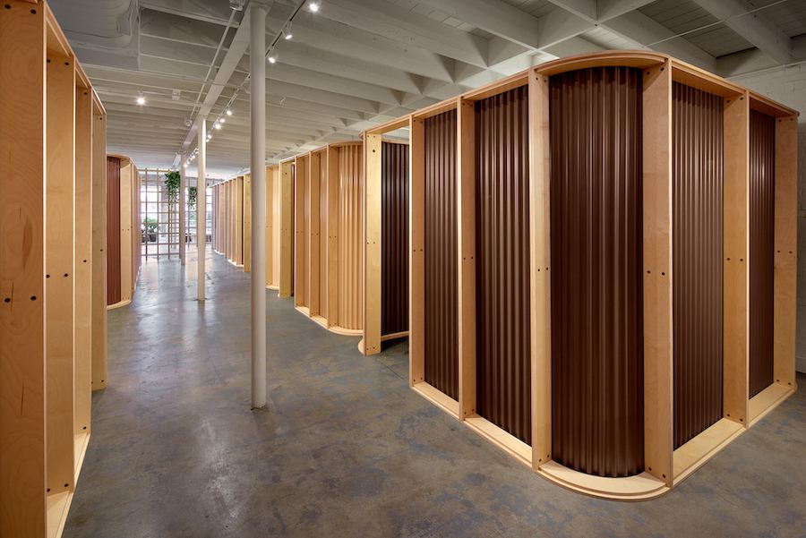 Tattoo booths built from plywood frames and brown corrugated steel at an Ephemeral tattoo studio