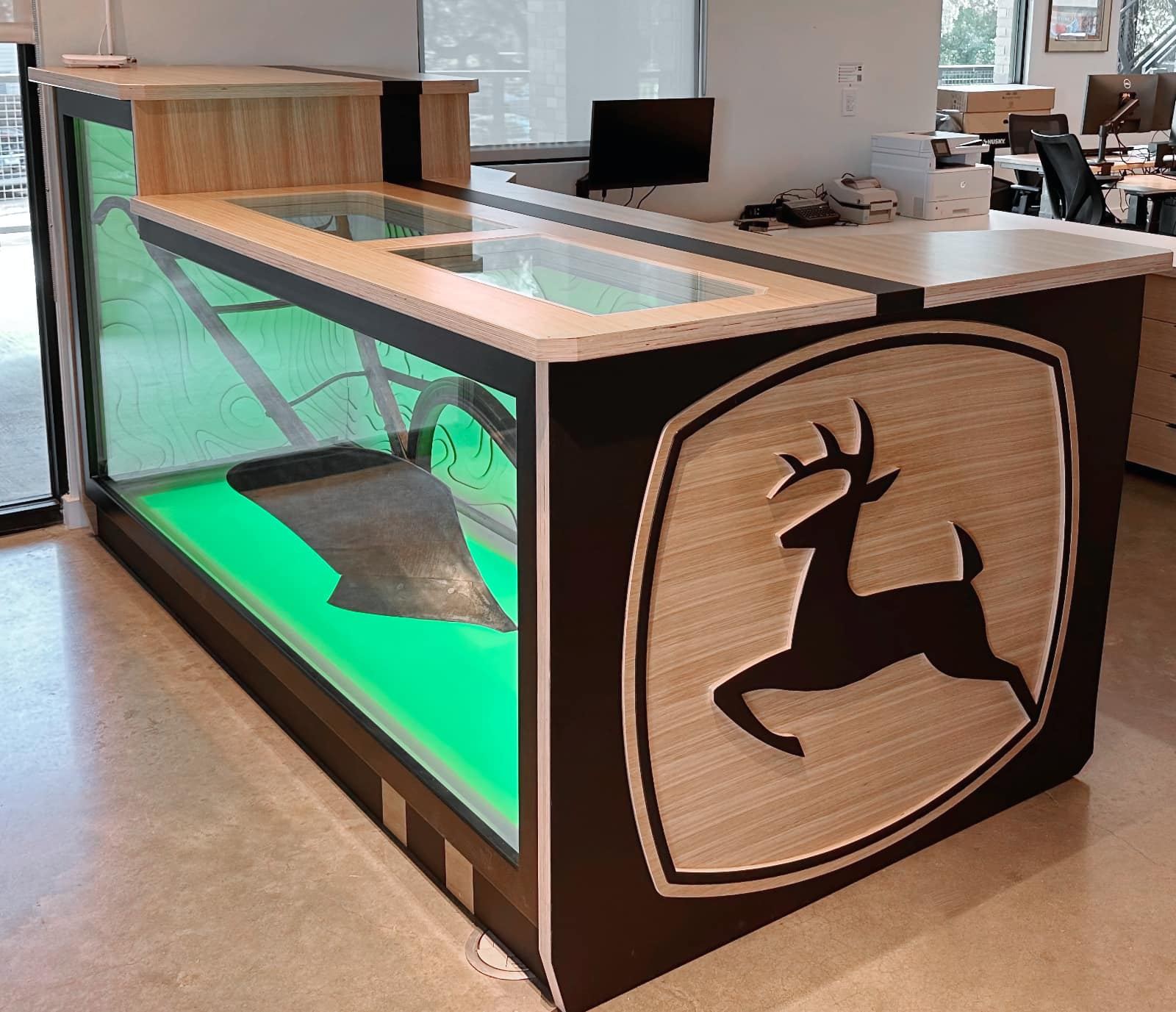 John Deere reception desk with a lit glass display case holding a historic plow