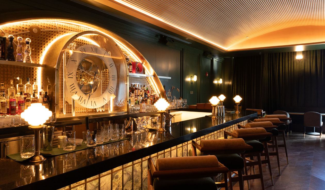 Bar at Jupiter Supper Club with a large clock set into a backlit arched back bar