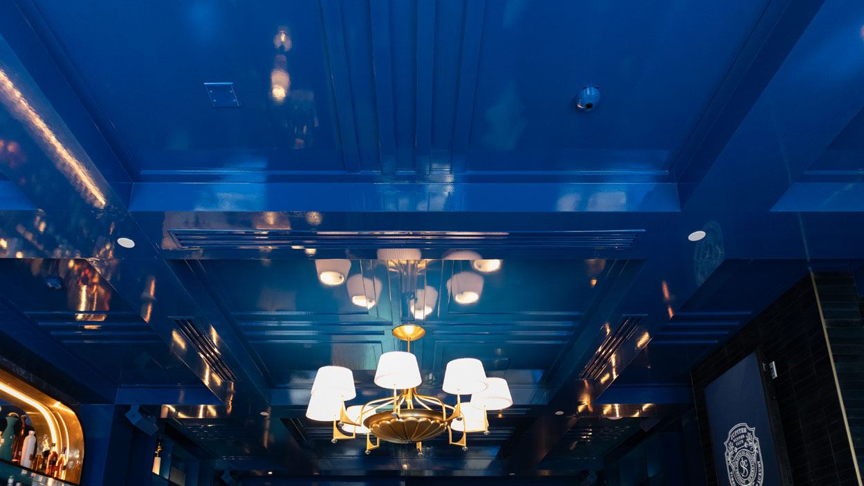 Glossy blue coffered ceiling with a brass chandelier