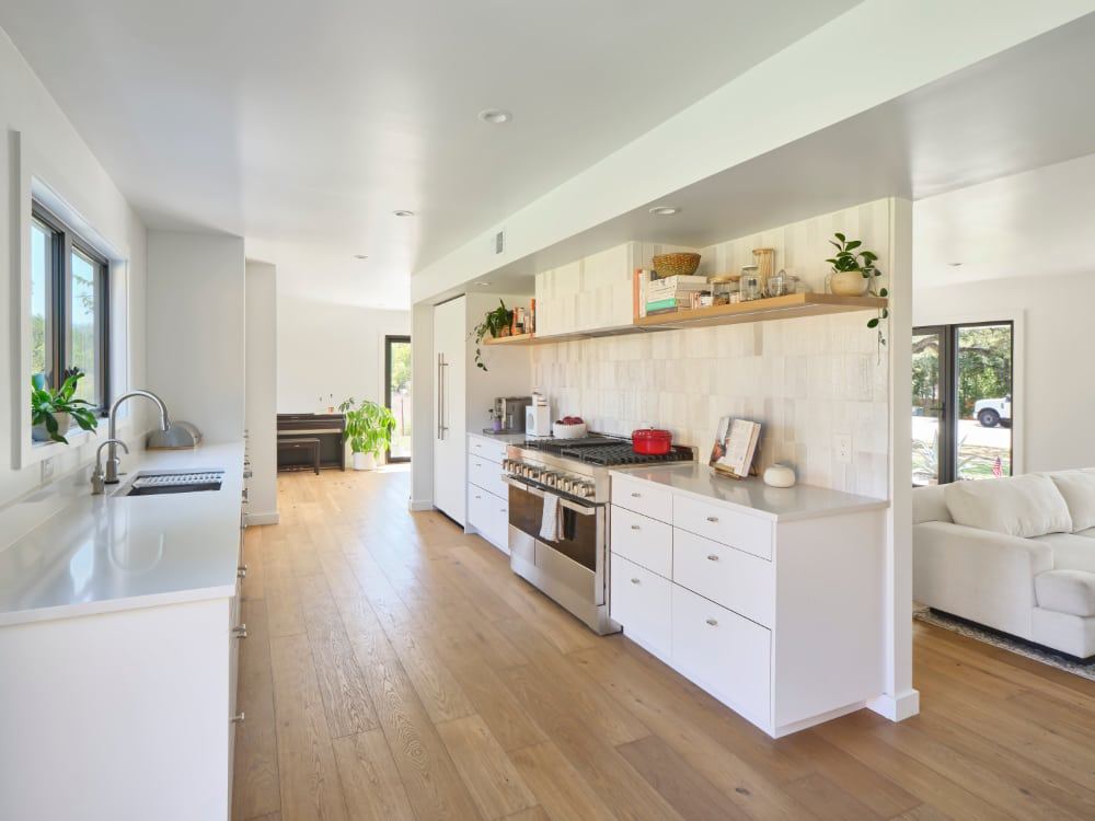 White galley kitchen with oak floors in a West Austin home