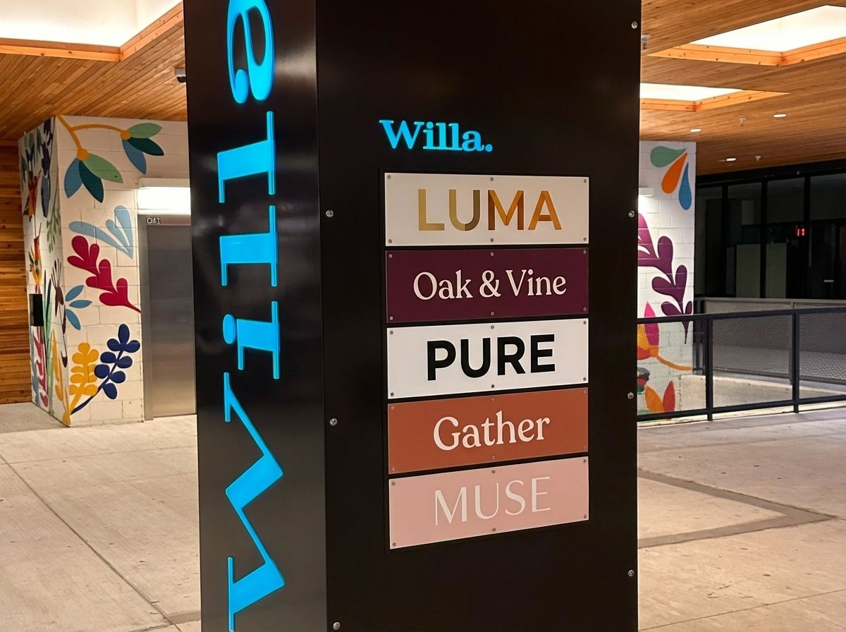 Black sign column with a tenant directory listing Luma, Oak & Vine, Pure, Gather and Muse, with the Willa name lit in blue