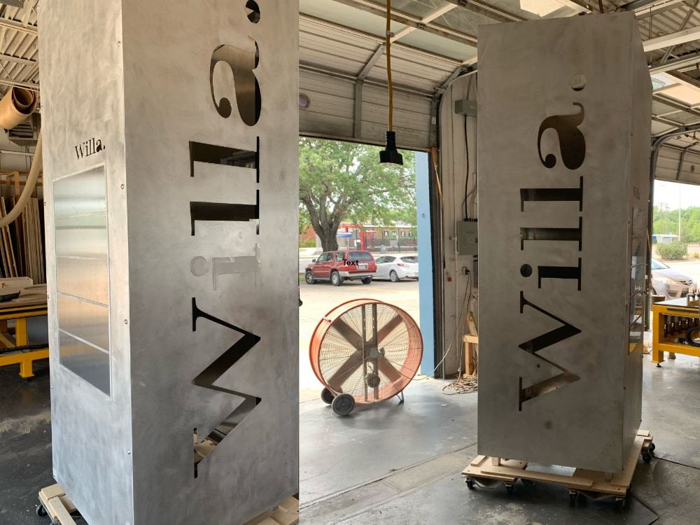 Two unfinished metal column wraps in the shop with Willa cut through their sides